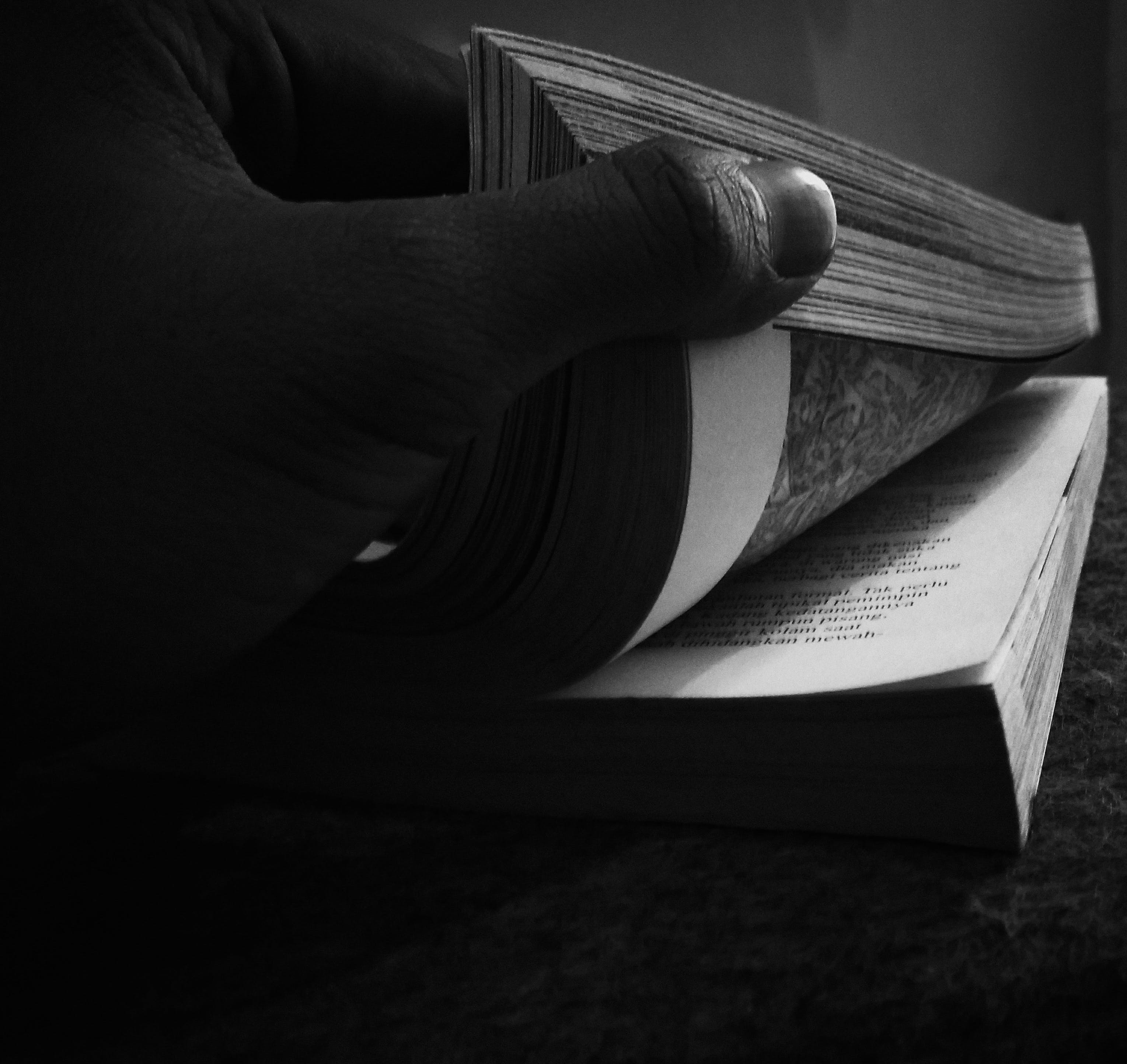 black & white photo of a hand flipping the pages of a corner of a book