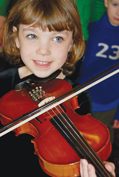 Child learning to hold a violin and bow.