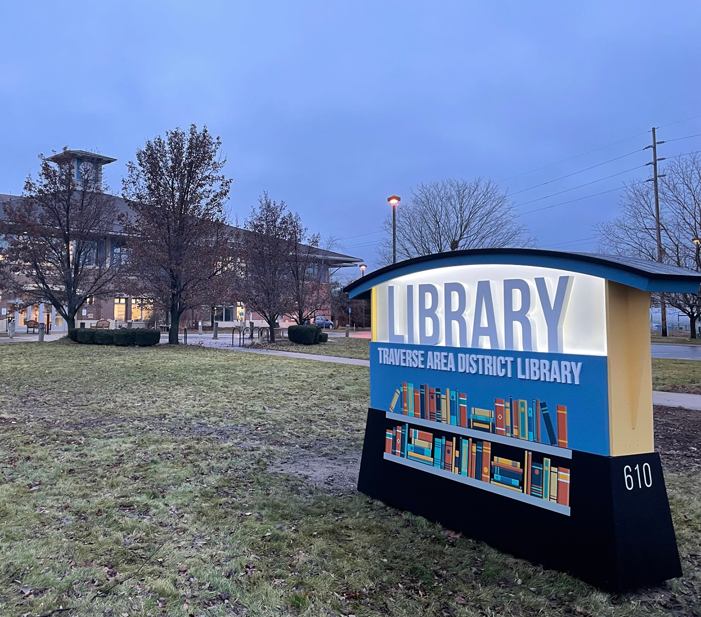 Sign outside the Main Library, Library is illuminated, over two bookshelves with the words Traverse Area District Library
