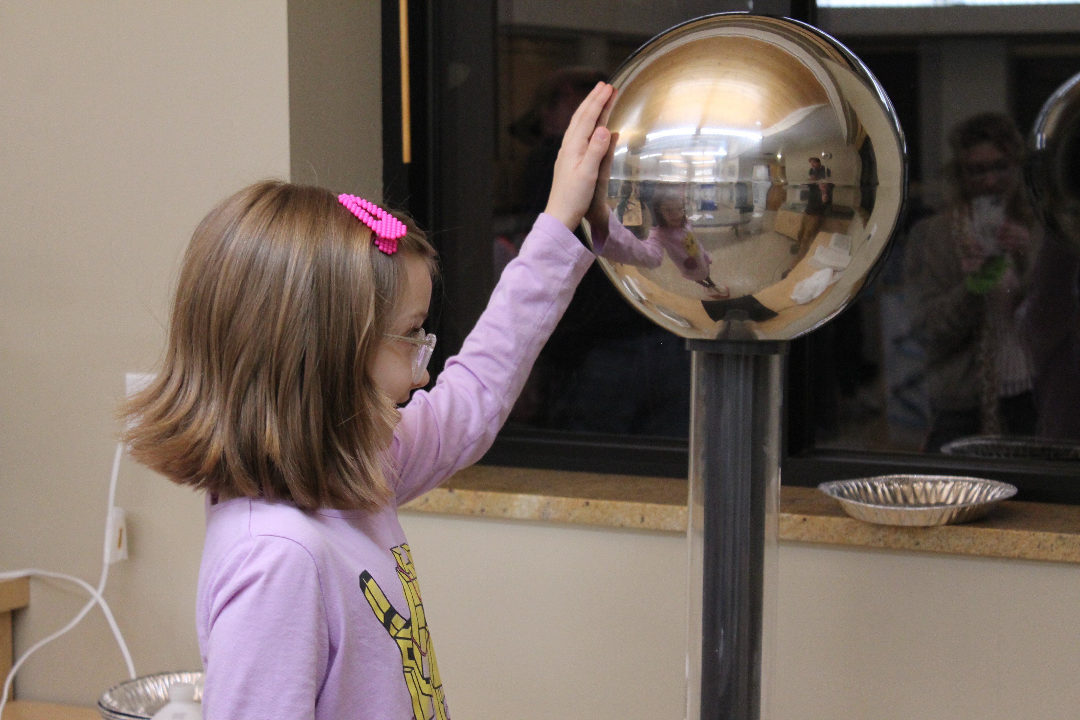 A girl putting her hand on a Van Der Graaf Generator from the Great Lakes Children's Museum.