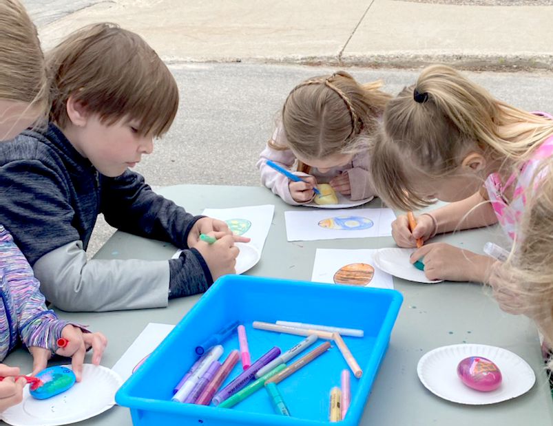 Group of children working on painted rock path project at KBL