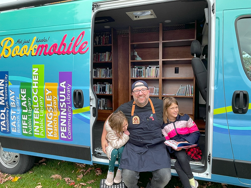 blue and green bookmobile with open door and family