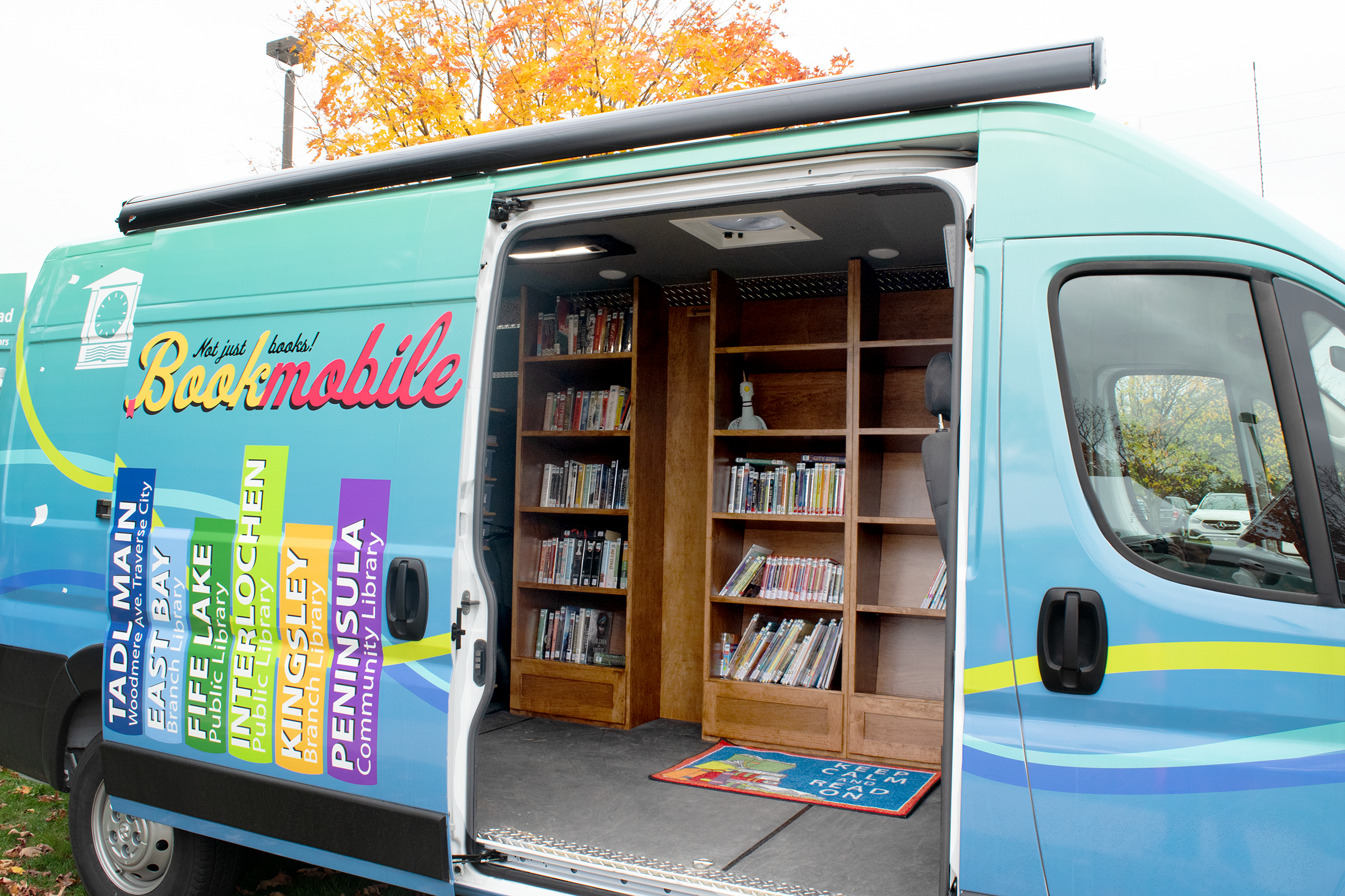 blue and green bookmobile with open door and wood shelves