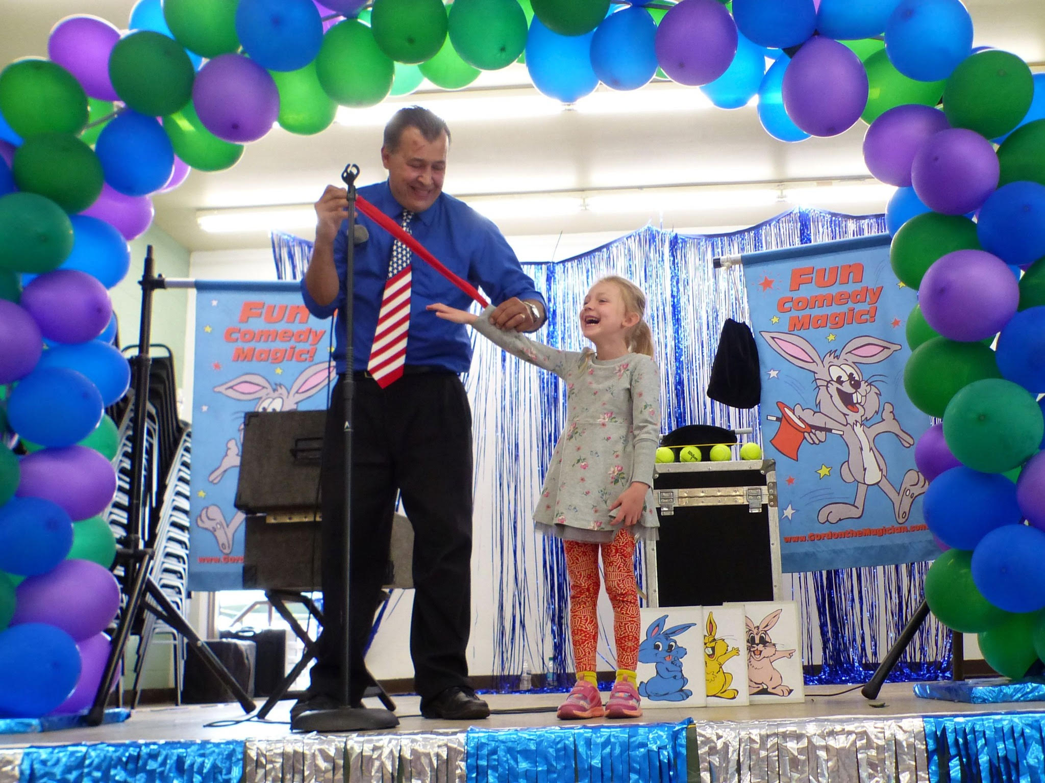 Gordon the Magician on stage while little girl laughs uproariously.