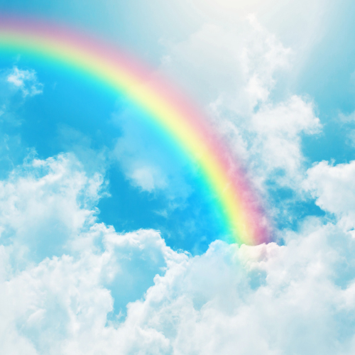 Image of a rainbow in a blue sky surrounded by clouds.