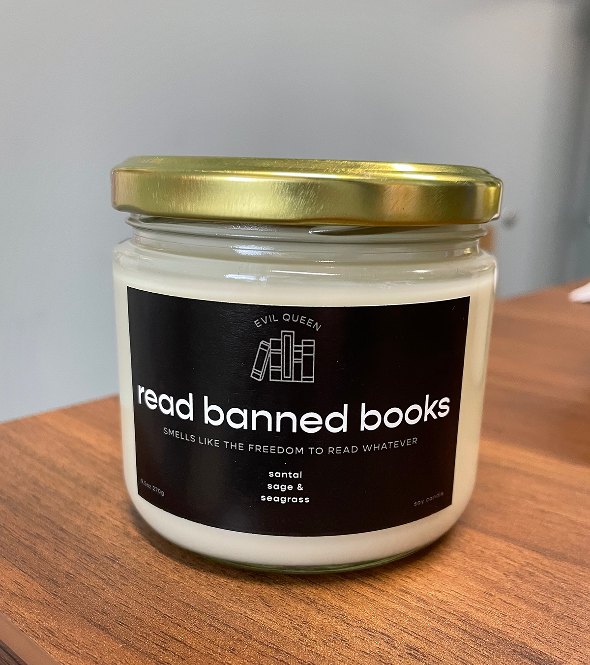 candle in a jar with a black label and gold top