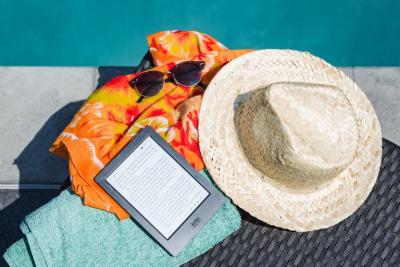 poolside straw sunhat with sunglasses and a newsprint ereader