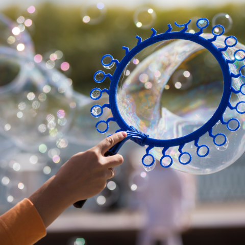 Image of a person's hand holding a multi-holed bubble wand.