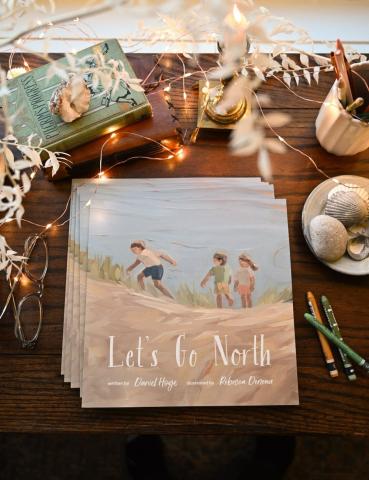 Books on a desk surrounded by shells, crayons and fairy lights