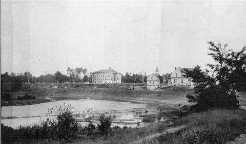 Black and white image of the newly constructed Carnegie Library on Sixth Street in Traverse City, Michigan, ca. 1903. On the far left is the Perry Hannah house. In the foreground is the Boardman River.