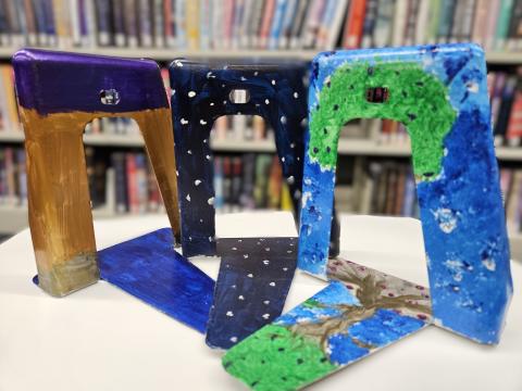 Three painted bookends in front of a book shelve.