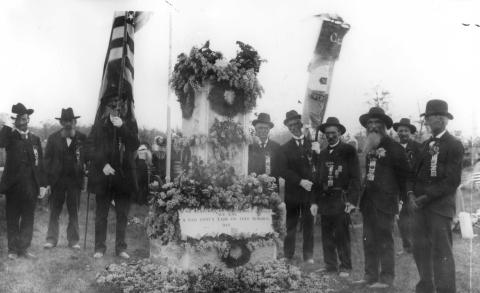 Image of the Civil War memorial at Oakwood Cemetery, Traverse City. There are several men in the photograph, some in uniform, who may have served.