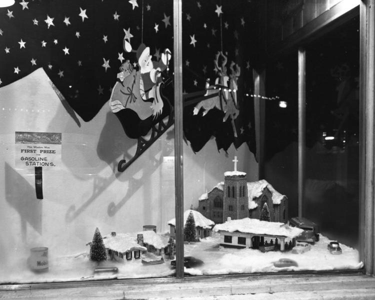 Local history photo of a downtown window featuring snowy hills, a town, and snowflakes