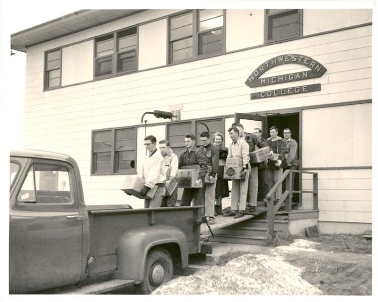 Black and white photo of people loading by a truck