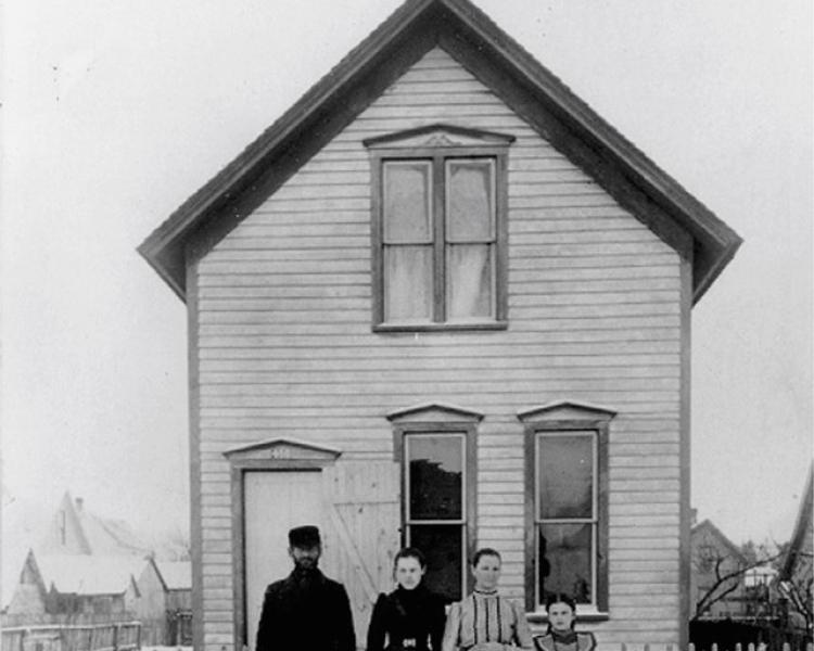Black and white photo of a house with a family outside