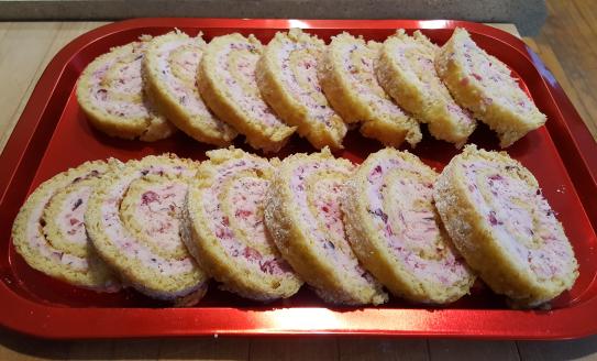 two rows of sliced cranberry orange cake roll on a tray